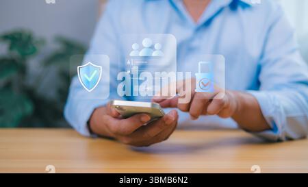 Person holding a smartphone interacts with a transparent overlay showing a login screen with security icons shield, padlock, user profiles. Online sec Stock Photo