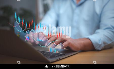 Businessman analyzing financial charts and stock market data on a laptop with candlestick graphs and digital analytics. Focus on investment, trading s Stock Photo