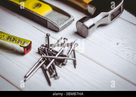 DIY tools are lying on pale workbench in flat design, with nails, hammer, level, measuring tape Stock Photo