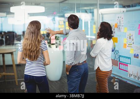 Team of business executives discussing over sticky notes in office Stock Photo