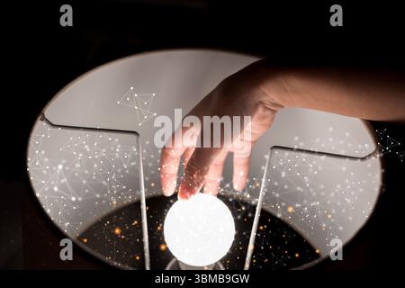 A human hand touching a glowing orb with abstract digital network particles floating around. Futuristic concept of connection, light, innovation, arti Stock Photo
