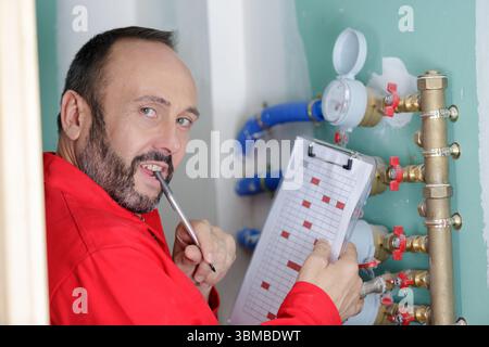 technician reading the water meter to check consumption Stock Photo