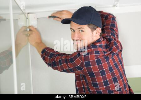 young guy repairs video surveillance on a light ceiling Stock Photo