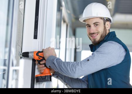 skilled professional using electric drill on the window Stock Photo