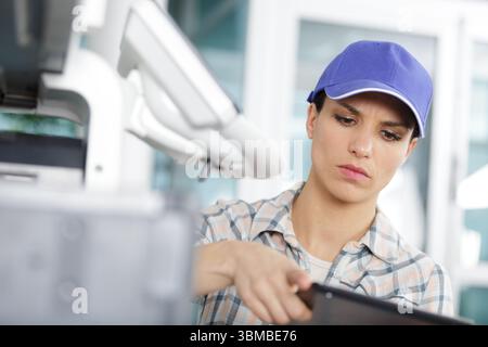 woman in casual outfit holding tablet and setting printer Stock Photo