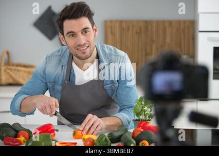 camera filming young smiling male blogger at the kitchen Stock Photo