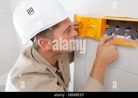 electrician installing electrical socket casing in bathroom Stock Photo
