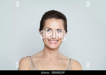 Charming mid aged mature woman looking at camera and smiling. Healthy face skin care beauty, middle age skincare cosmetics and cosmetology concept Stock Photo