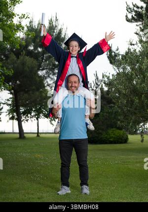 A boy celebrating his primary school graduation with his father Stock Photo