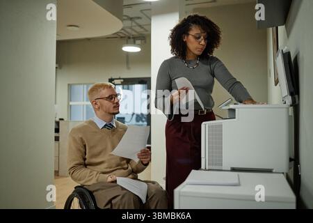Young Caucasian Man with Disability Collaborating with Black Woman Stock Photo