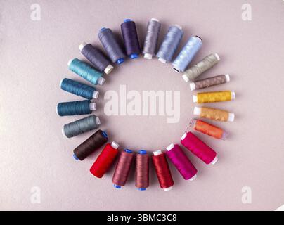 Spools with multi-colored threads form a circle on a light background, copy space Stock Photo