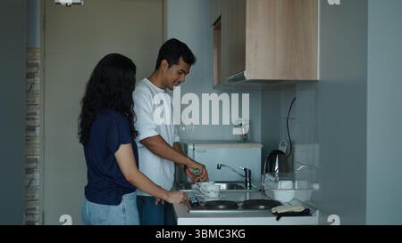 Couple brewing tea, sharing intimate morning moment in sleek minimalist kitchen Stock Photo