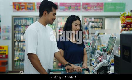 Young couple using self checkout kiosk in a convenience store, making purchasing process faster and more efficient Stock Photo