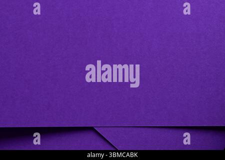 Elegant designer paper in bright and dark violet purple tones with matte texture and monochrome surface. Overlapping sheets create simple geometric li Stock Photo