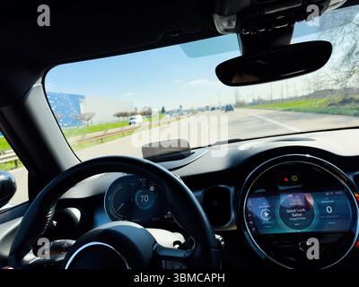 Paris, France - Mar 27, 2025: Close-up interior of MINI electric car driving on highway with visible digital dashboard, Apple CarPlay and hand on steering wheel Stock Photo