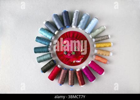 Pillow with pins in the shape of a hat and multi-colored threads, sewing supplies Stock Photo