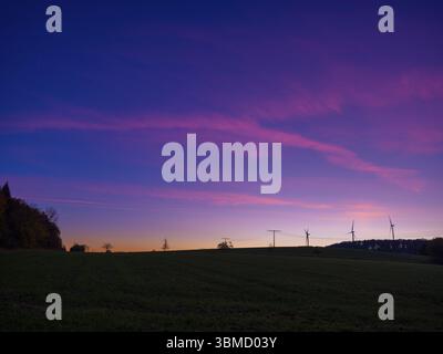Red-blue sky at sunset over a meadow with wind turbines and power lines, Bad Arolsen, Hesse, Germany, Europe Stock Photo