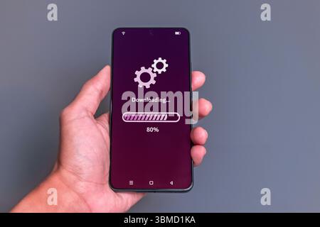 Downloading process bar on phone screen. Man using smartphone to download media or update software. Stock Photo