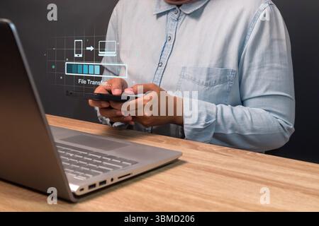 Backup, copy file or exchange data concept. Woman transfer files from mobile phone to laptop. Stock Photo