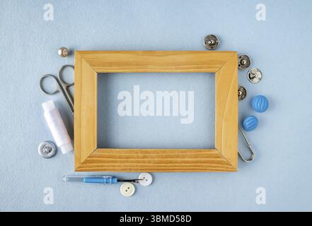 A wooden frame around which are buttons, scissors, threads, a ripper, buttons, sewing accessories Stock Photo