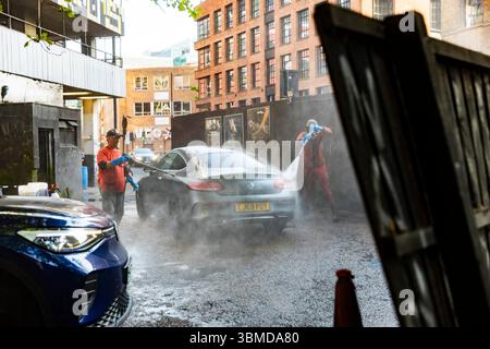 London, UK, 12 May 2025, Two Caucasian men, one young and one mature, are washing a gray Mercedes-Benz C-Class coupe at an outdoor car wash, generatin Stock Photo