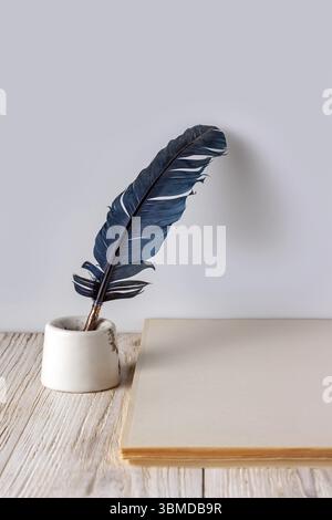 Feather, inkwell and stack of sheets of paper on white wooden background, copy space Stock Photo