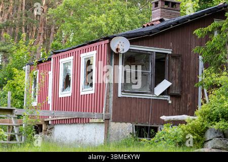 Derelict wooden house with broken windows and rusty satellite dish Stock Photo