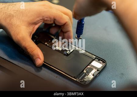 Expert Phone Repair Technician Working on Smartphone Internal Components at a Workshop in the Afternoon Stock Photo