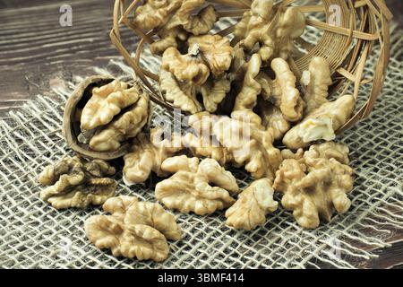 Peeled walnuts lie in a basket on a dark table. Stock Photo