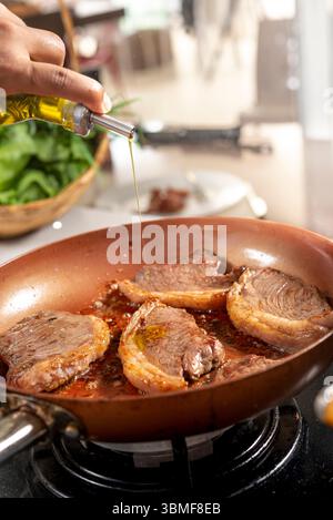 Chef cooking steaks on a frying pan in a restaurant kitchen Stock Photo