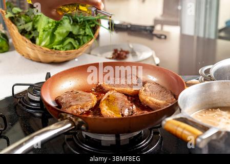 Chef cooking steaks on a frying pan in a restaurant kitchen Stock Photo