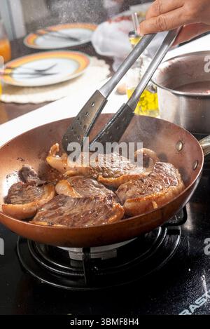 Chef cooking steaks on a frying pan in a restaurant kitchen Stock Photo