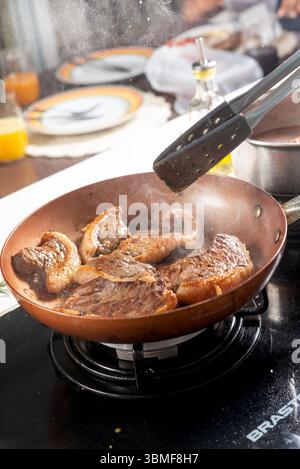 Chef cooking steaks on a frying pan in a restaurant kitchen Stock Photo