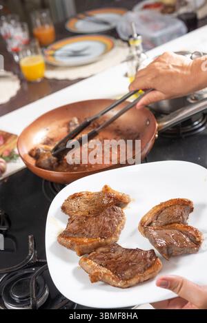 Chef cooking steaks on a frying pan in a restaurant kitchen Stock Photo