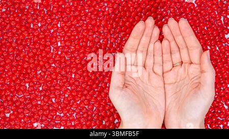 Female Hands holding together. Mockup design. A Pile of Heart Shaped Red Candies for Love and Romance on White Background. Stock Photo