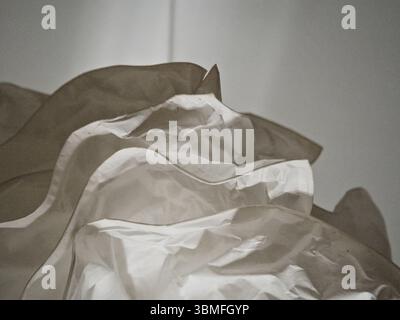 Abstract image of white papery textures forming a three-dimensional circular structure, viewed from below on a white background. Stock Photo