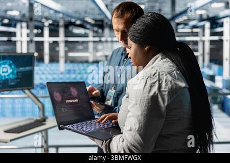 Server hub colleagues using AI to detect abnormal network traffic patterns caused by hacker attack. Data center specialists deploying artificial intelligence countermeasures to neutralize hacking Stock Photo