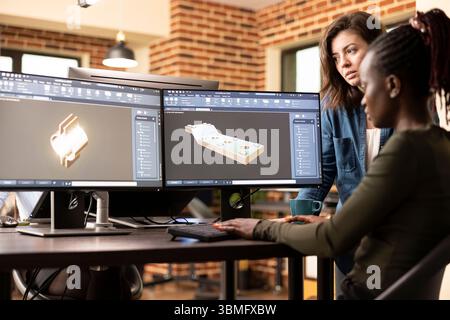 Black and caucasian female engineers collaborating at desk, trying to develop the geometry of 3d design for a construction company. African american developer using cad software on a multi monitor. Stock Photo