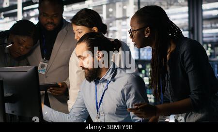 Admins doing brainstorming in server hub, reviewing machine learning code and LLM visualization dashboards. Data center IT experts using computer to monitor AI infrastructure performance, camera A Stock Photo