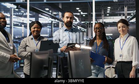 Happy data center engineering team members collaborating on neural network software development. Smiling server hub coworkers implementing machine learning technology in workplace, camera A Stock Photo