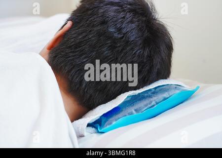 Young man resting in bed with ice pillow due to heat stroke caused by intense heat Stock Photo