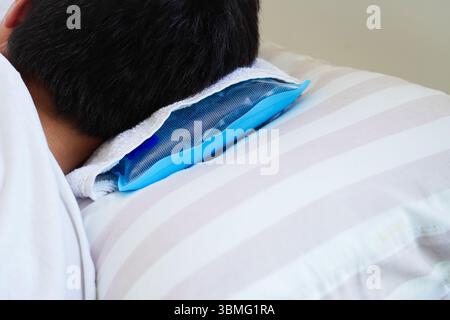 Young man resting in bed with ice pillow due to heat stroke caused by intense heat Stock Photo