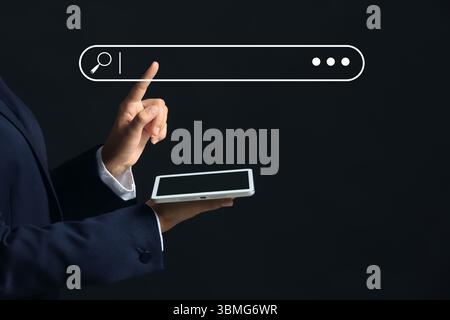 Businessman with tablet computer using web search engine on dark background Stock Photo