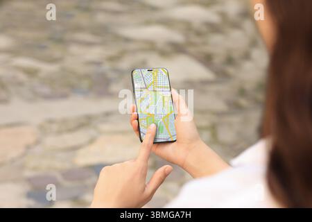 Woman looking at city map on her mobile phone outdoors, closeup Stock Photo