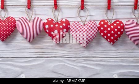 Valentine fabric hearts hanged on rope on white wooden background Stock Photo