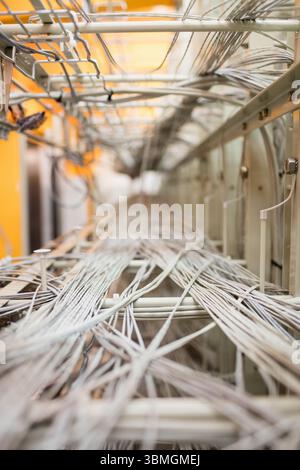 White and gray network cables are stretching along metal trays in 3D render server room Stock Photo