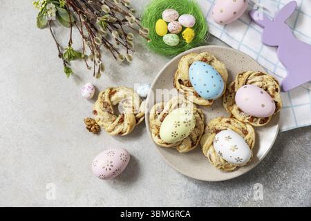 Easter composition. Sweet Italian Easter Bread Rings from puff pastry and dyed eggs on a stone background. View from above. Copy space Stock Photo