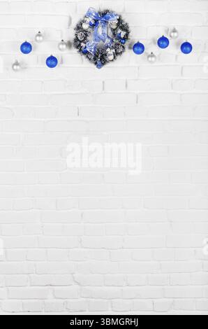 Christmas blue and silver balls and wreath on white brick wall holiday background Stock Photo