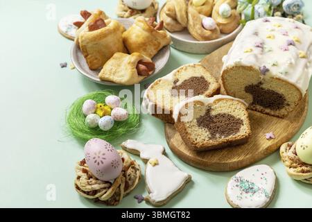 Festive dinner, Easter brunch. Happy Easter holiday food baking puff pastry and cupcake with Easter Bunny on pastel green background. Copy space Stock Photo