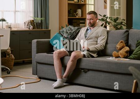 Middle Aged Man Working Remotely Using Laptop While Sitting Indoors Stock Photo